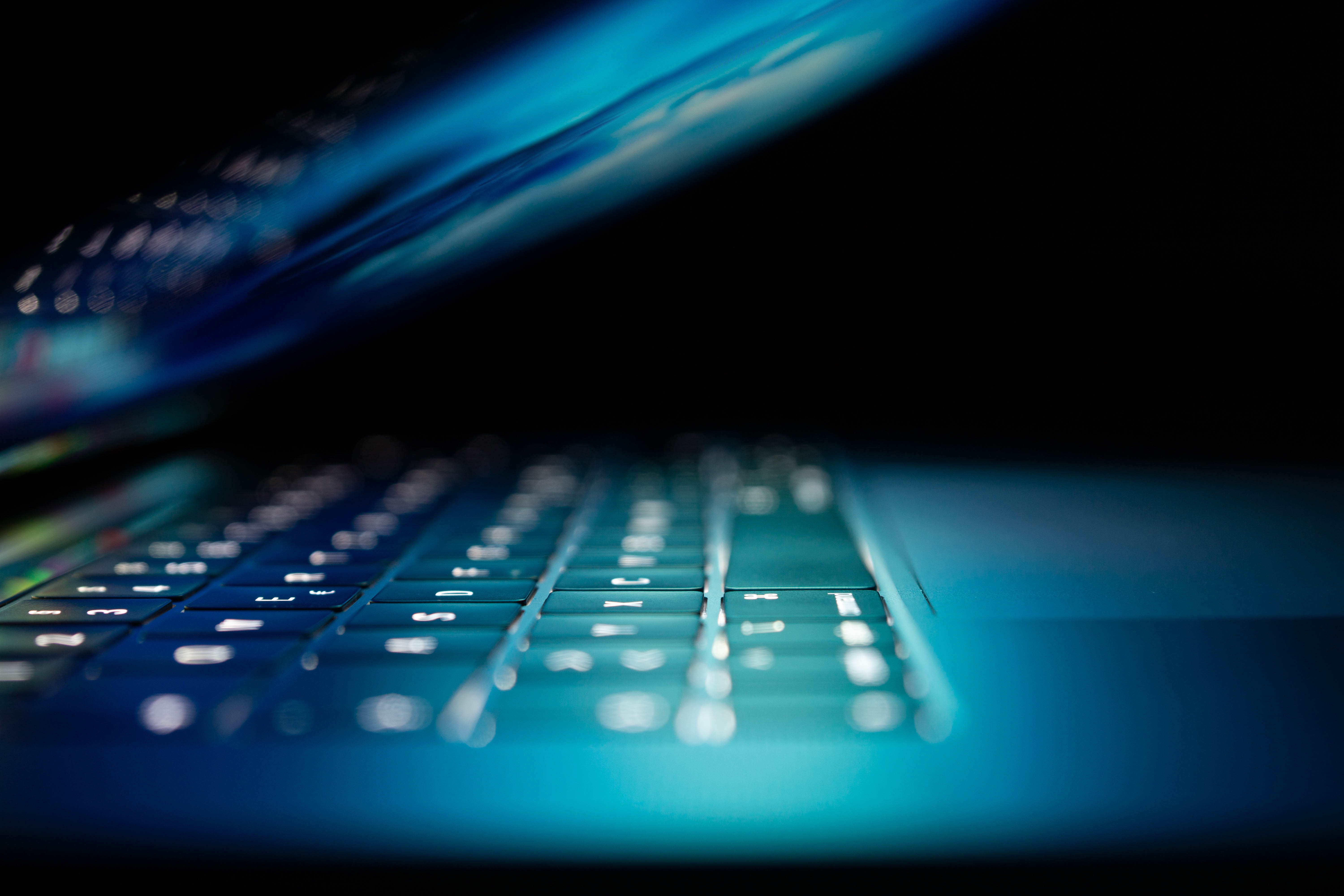 laptop där skärmen lyser upp tangentbordet med blått ljus.
