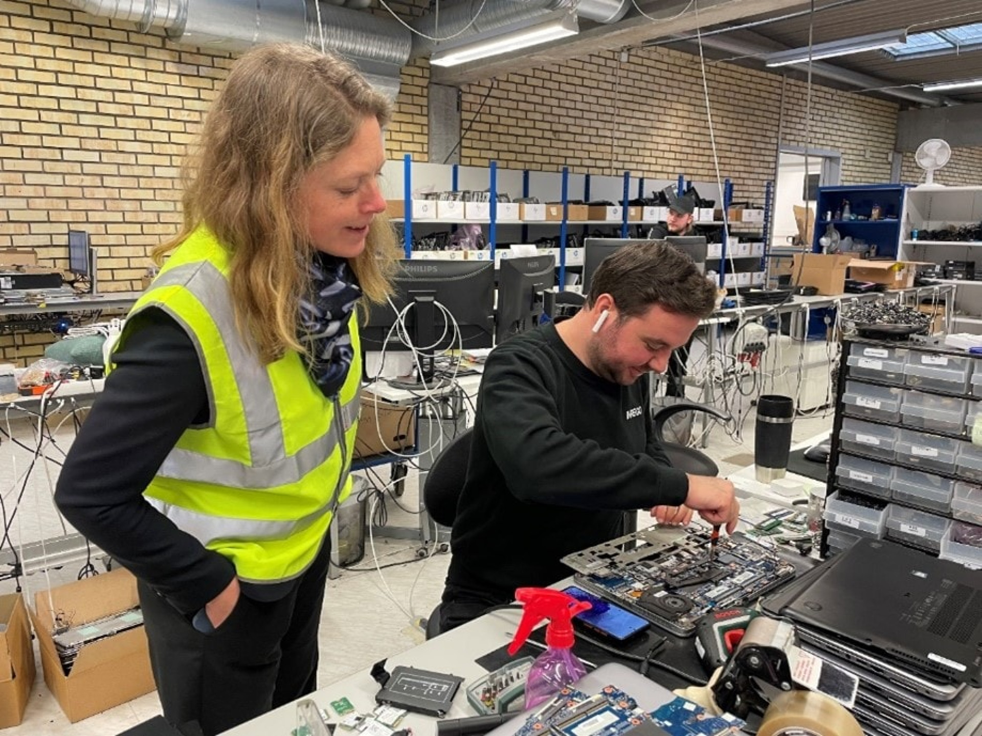 Stina Larsson (C) ser på när Inregos tekniker, Said Kouki, renoverar en bärbar dator för att ge den en längre livstid.
