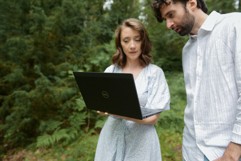 Kvinna och man med laptop i skogen.