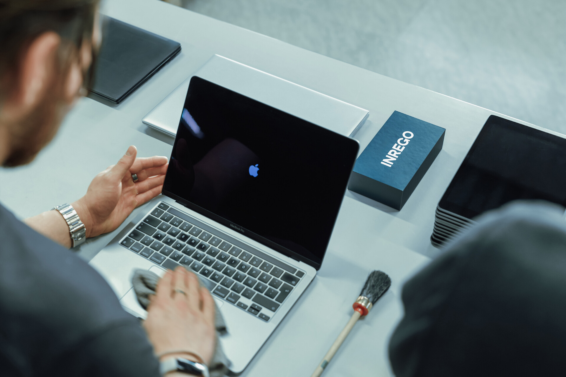 Man putsar Macbook.