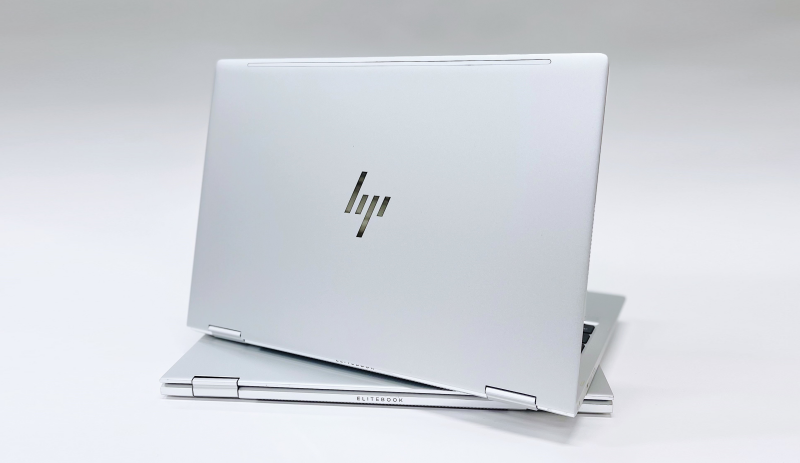 En silvrig HP-laptop som stör öppnad på en stängd likadan dator.
